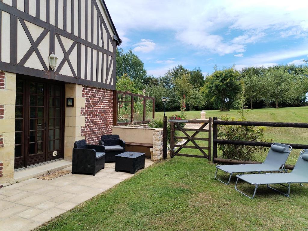 eine Terrasse mit Stühlen, einem Tisch und einem Zaun in der Unterkunft Domaine le Manège - Gite Le Phare - près d'Etretat in Sainte-Marie-au-Bosc