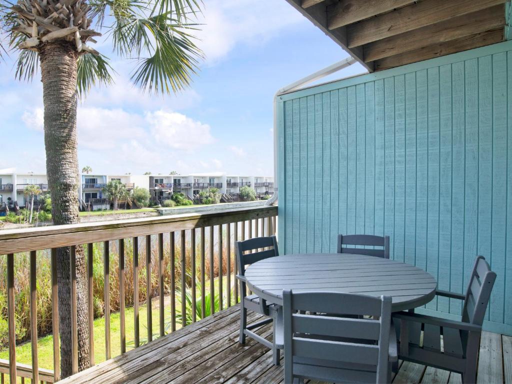 a table and chairs on a deck with a palm tree at Coconuts Beach House in Pensacola Beach