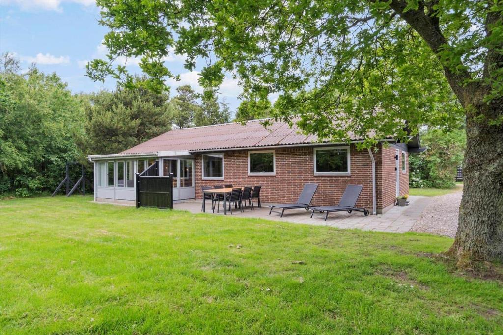 198-Ringkobing-Bogealle-8 في Nørby: منزل من الطوب مع طاولة وكراسي في الفناء