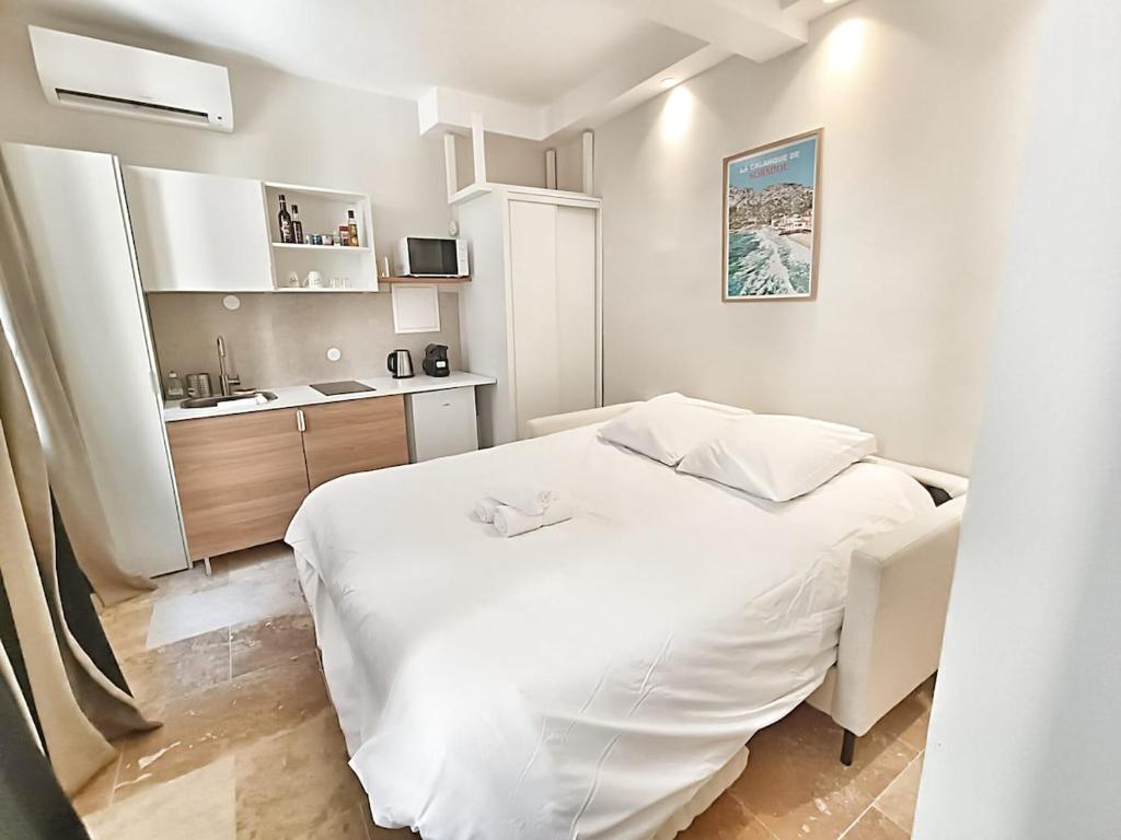 エクス・アン・プロヴァンスにあるLe Loubon By La Familiaの小さなベッドルーム(白いベッド1台付)、キッチンが備わります。