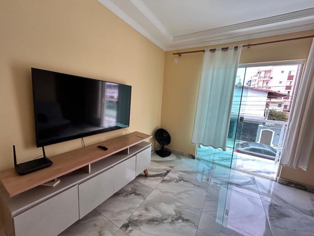 een woonkamer met een flatscreen-tv aan de muur bij Apê Dunas do Forte in Cabo Frio