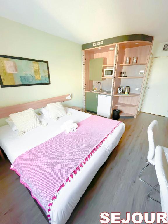 une chambre avec un grand lit avec une couverture rose dans l'établissement 5 minutes du Parc de la Villette - Charmant studio, à Pantin