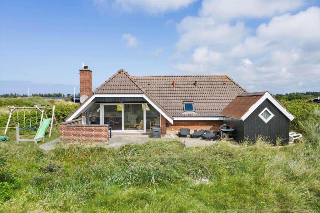 een klein huis met een speeltuin in een veld bij 2250-Ringkobing-Vestklitvej-25 in Klegod