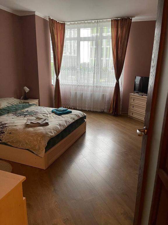 a bedroom with a bed and a large window at Затишні апартаменти in Lviv