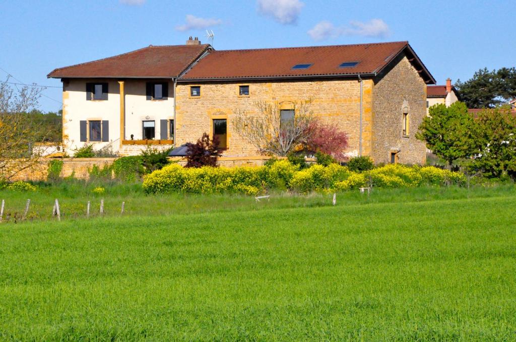 a large brick house with a green field in front of it at Le Clos du Cher en Beaujolais in Saint-Germain-Nuelles