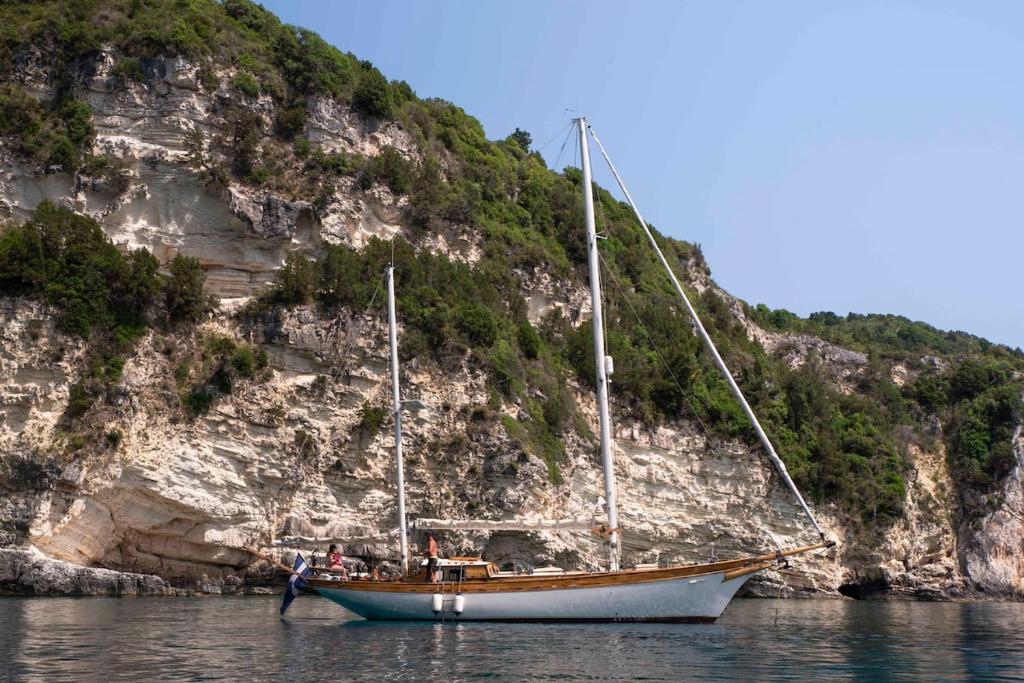 a boat sitting on the water next to a mountain at Nereid in Nisída Ágios Nikólaos
