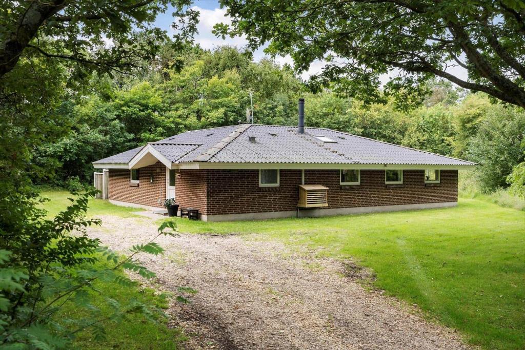 a small brick house in the middle of a yard at 1129-Ringkobing-Irisvej-11 in Nørby