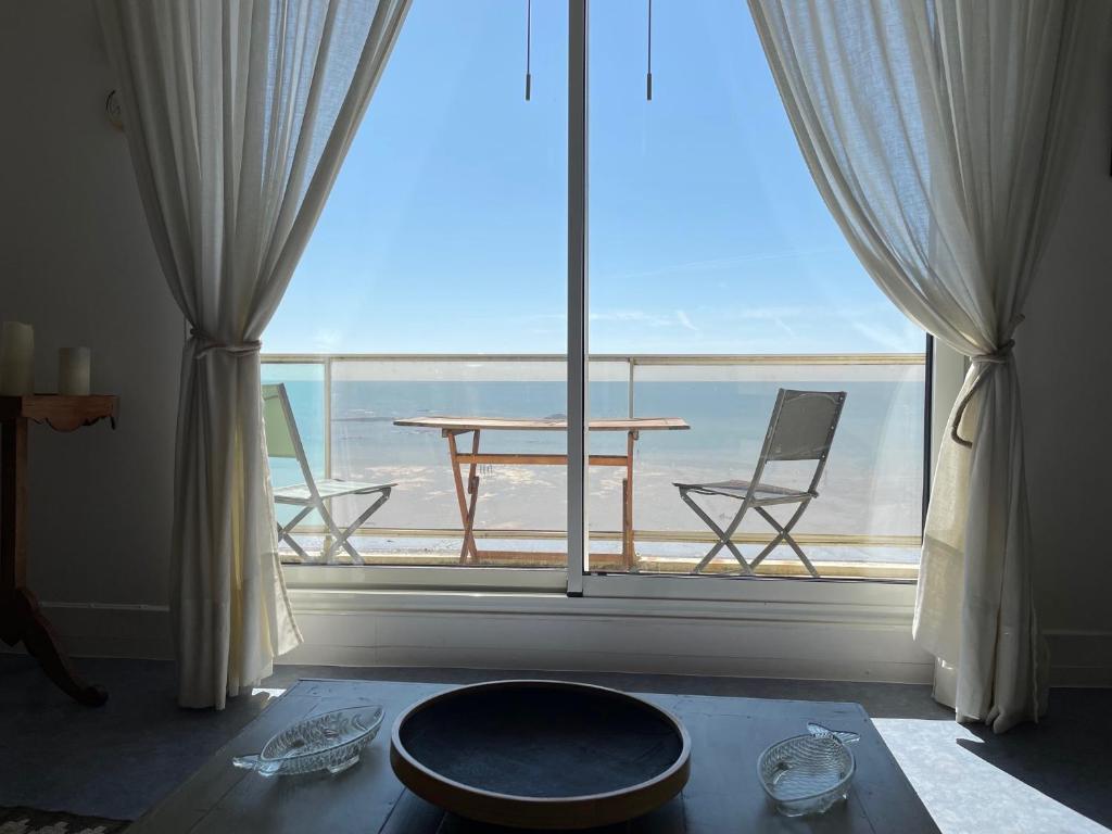 Zimmer mit einem großen Fenster mit einem Tisch und Stühlen in der Unterkunft La Corniche in Agon Coutainville