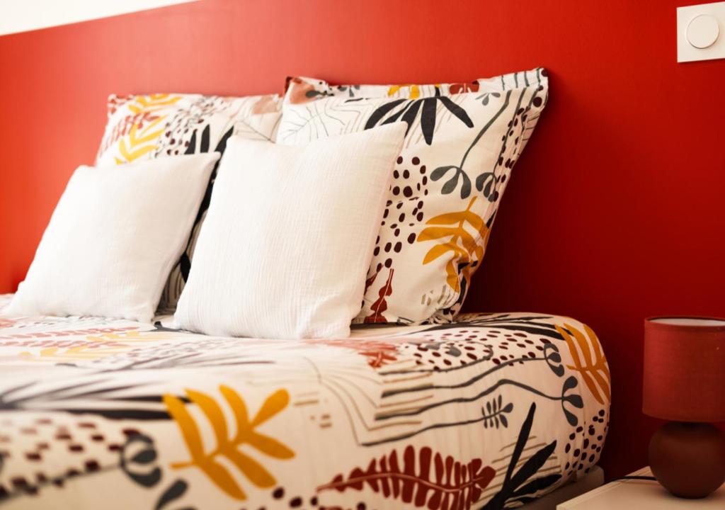 ein Bett mit weißen Kissen und einer roten Wand in der Unterkunft Appartement Villa Losa in Biscarrosse