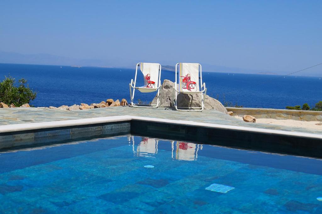 two chairs and a swimming pool with the ocean in the background at NISIDA Resort & Meditation center - Adult only in Áno Fanárion