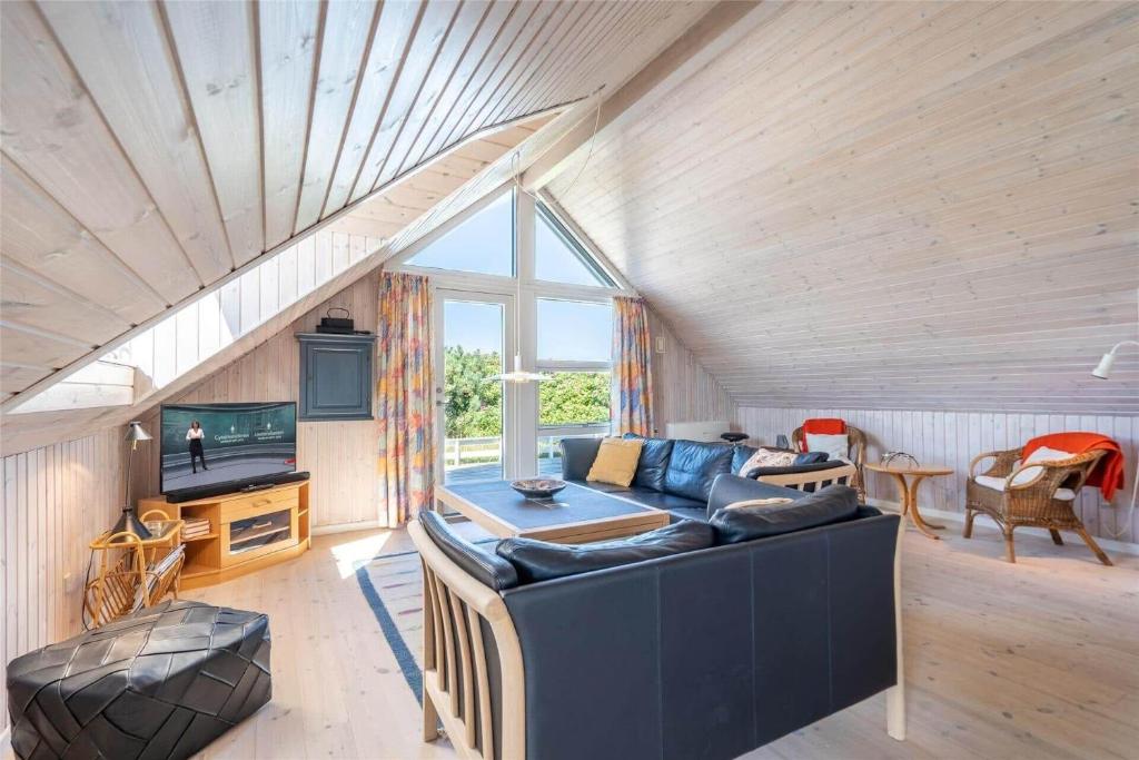 a living room with a blue couch and a tv at 221-Ringkobing-Havklitvej-72 in Klegod
