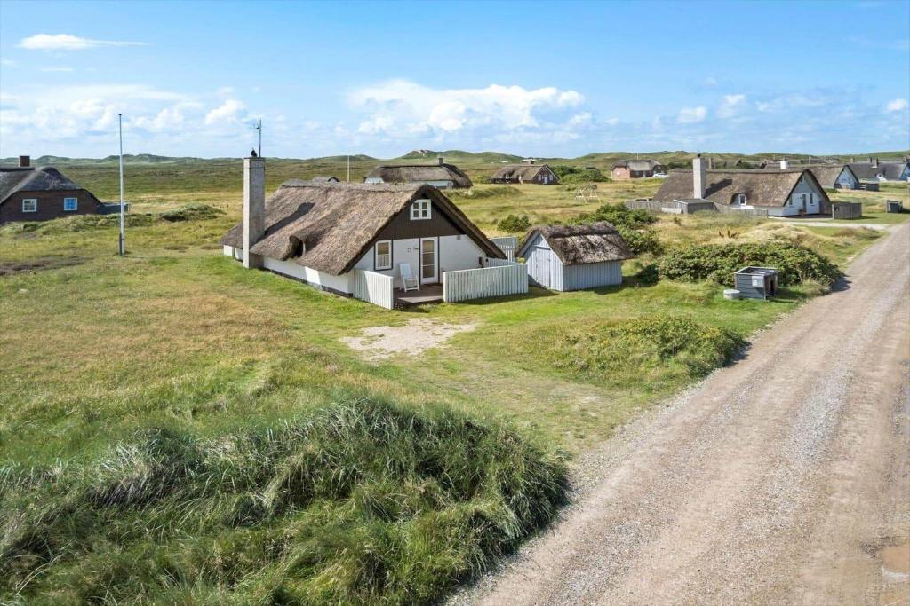 a house on a field next to a dirt road at 207-Ringkobing-Nordso-Ferievej-27 in Nørre Lyngvig