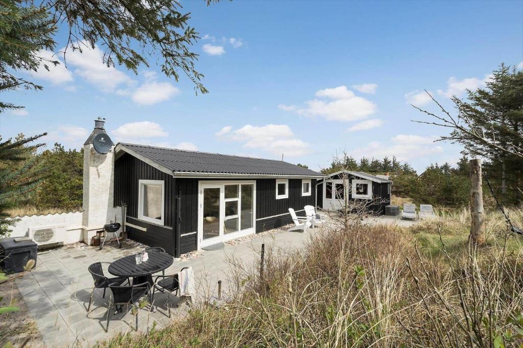 una casa nera con patio e tavolo di 1083-Ringkobing-Spaettedalen-6 a Nørby