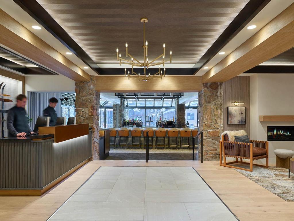 a lobby of a restaurant with a man standing at a counter at Stonebridge Inn in Snowmass Village