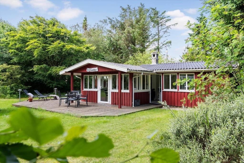 een rood huisje met een terras in een tuin bij 1134-Ringkobing-Egernvej-12 in Nørby