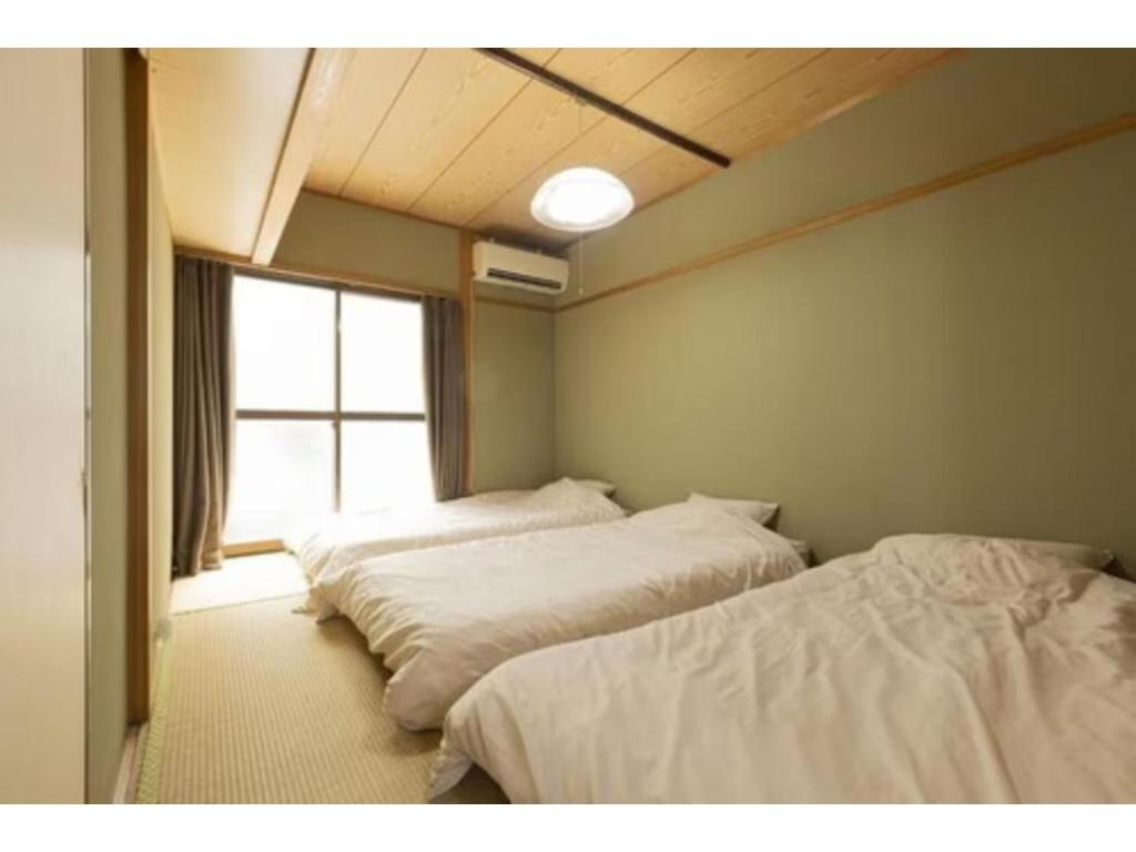 two beds in a room with a window at Guest House Shine Bright - Vacation STAY 19292 in Fukuoka