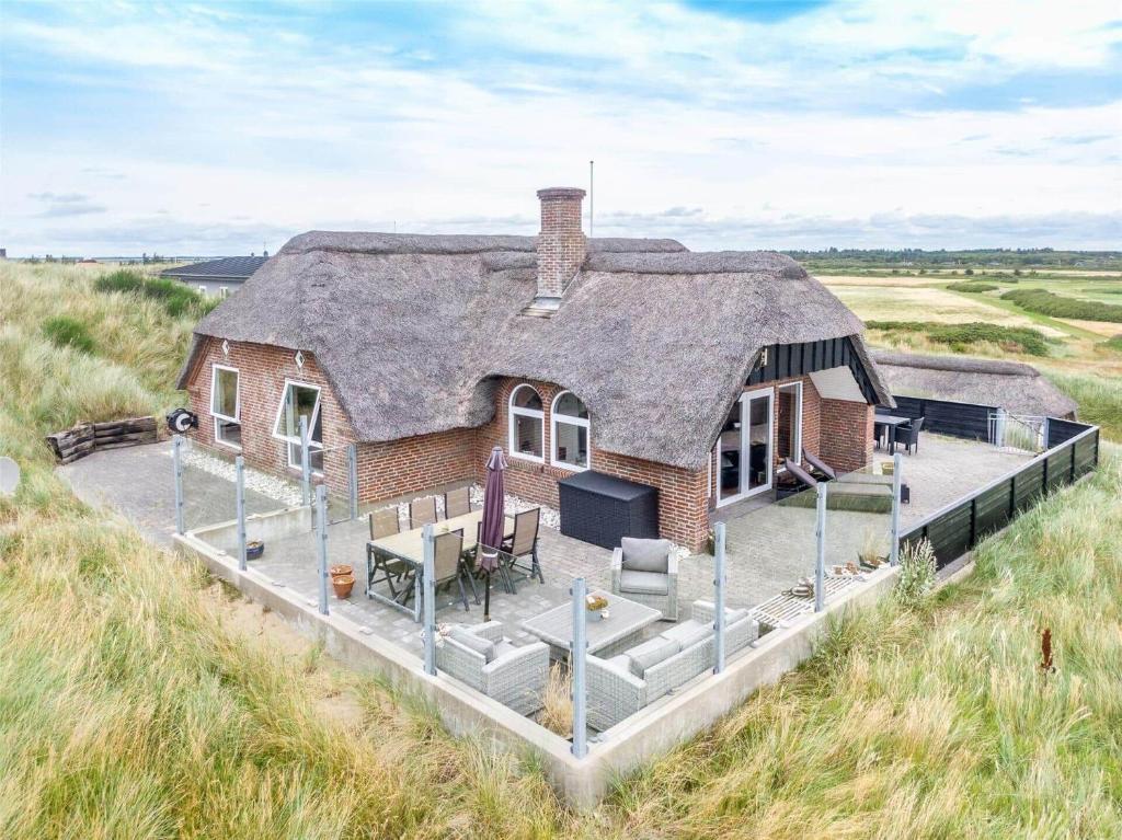a house with a thatched roof in a field at 152-Ringkobing-Regnspovedalen-6 in Nørby