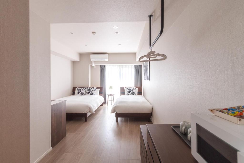 LANG HOTEL Kameido - Vacation STAY 79286v في طوكيو: غرفة نوم بسريرين وطاولة في غرفة