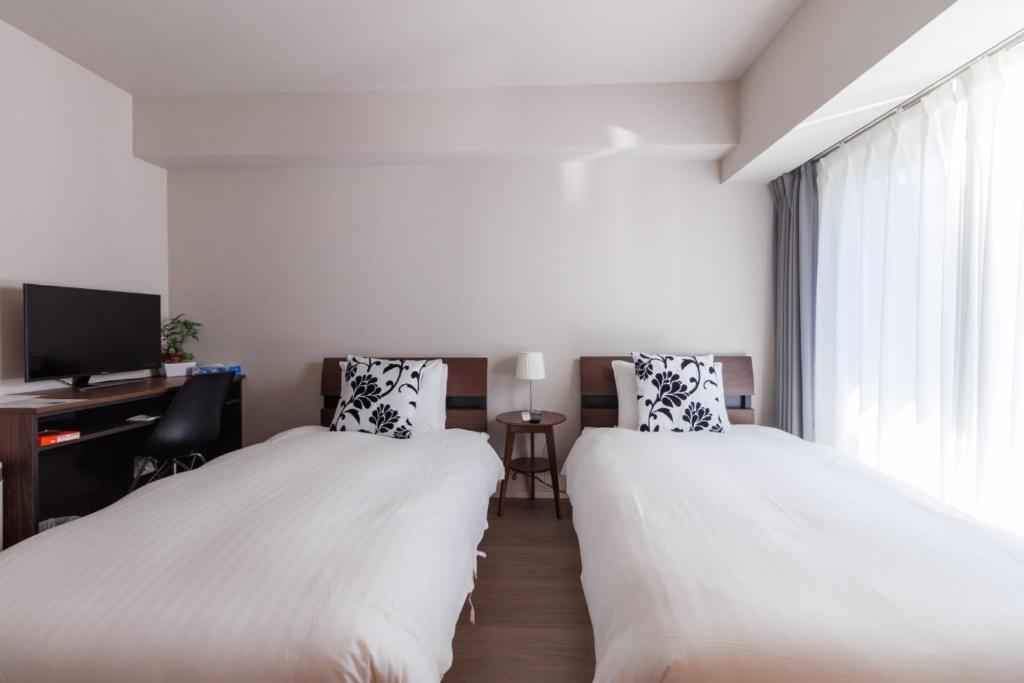 two beds in a room with a desk and a tv at LANG HOTEL Kameido - Vacation STAY 79388v in Tokyo