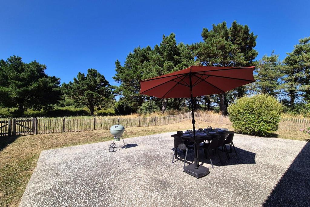 une table et des chaises sous un parapluie rouge dans l'établissement country house Land and sea, à Saint-Hilaire-de-Talmont