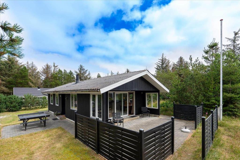 une maison noire avec une terrasse et une table de pique-nique dans l'établissement 233-Ringkobing-Milevej-38, à Klegod