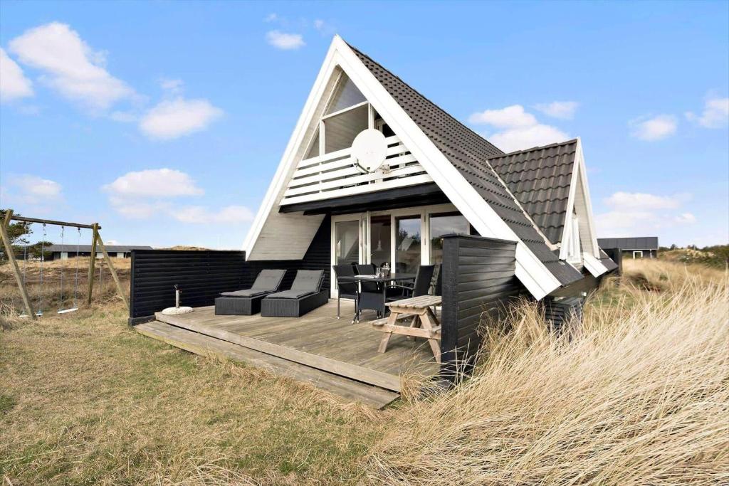 ein kleines Haus auf einer Holzterrasse auf einem Feld in der Unterkunft 260 Ringkøbing - Vestklitvej 13 in Klegod