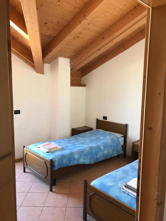 two beds in a room with wooden ceilings at Appartamento Widmann Silvano in Cles