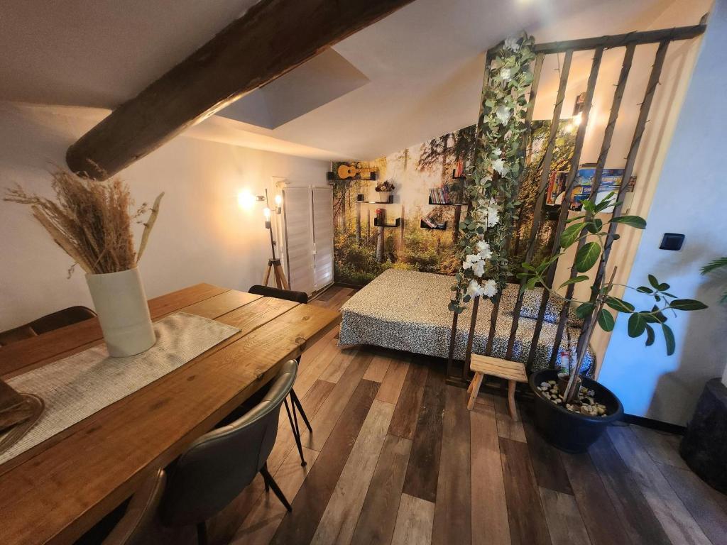 ein Wohnzimmer mit einem Tisch und einem Bett mit Blumen in der Unterkunft Le Celeste Maison de Village avec toit terrasse in Gréoux-les-Bains