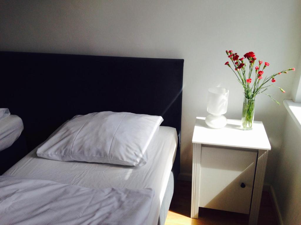 a bed with a vase of flowers on a night stand at Hostel Octopus Gdańsk in Gdańsk