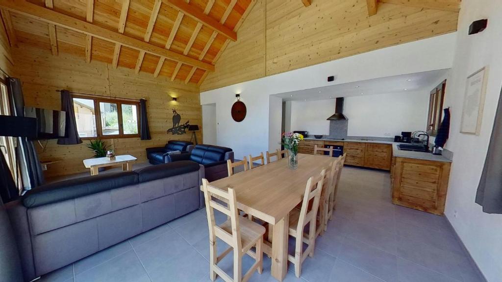a dining room and kitchen with a table and a couch at CASA-Grand Laus: Duplex familial sauna et jacuzzi in Aiguilles