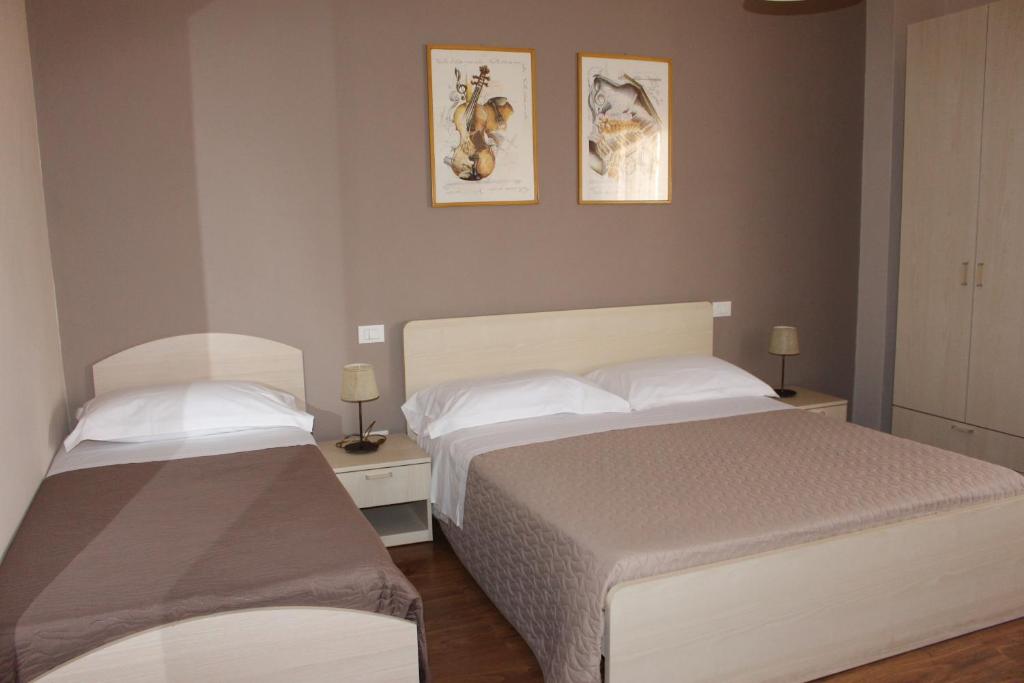 a bedroom with two beds and two lamps and pictures on the wall at B&B I' Chivi in Incisa in Valdarno