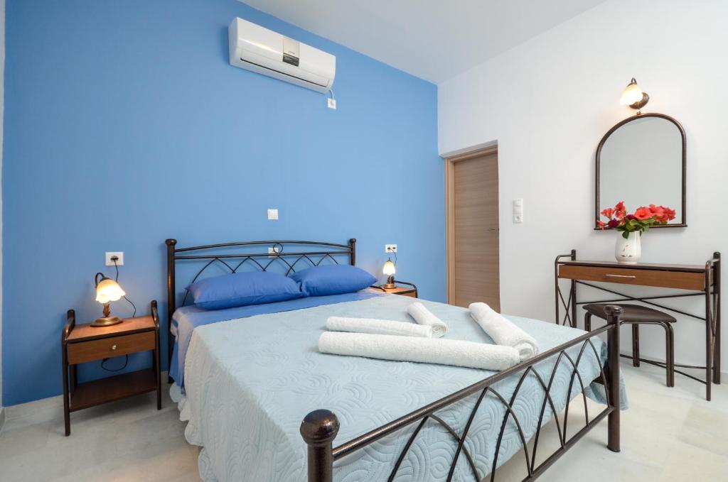 - une chambre bleue avec un lit, un bureau et un miroir dans l'établissement Surfer Studios, à Mikri Vigla