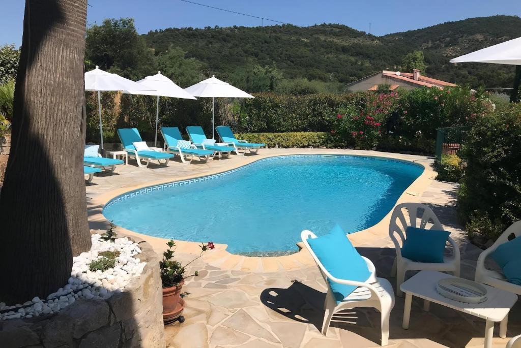 une piscine avec des chaises bleues et des parasols dans l'établissement CASA-Villa des Oiseaux, aux Issambres