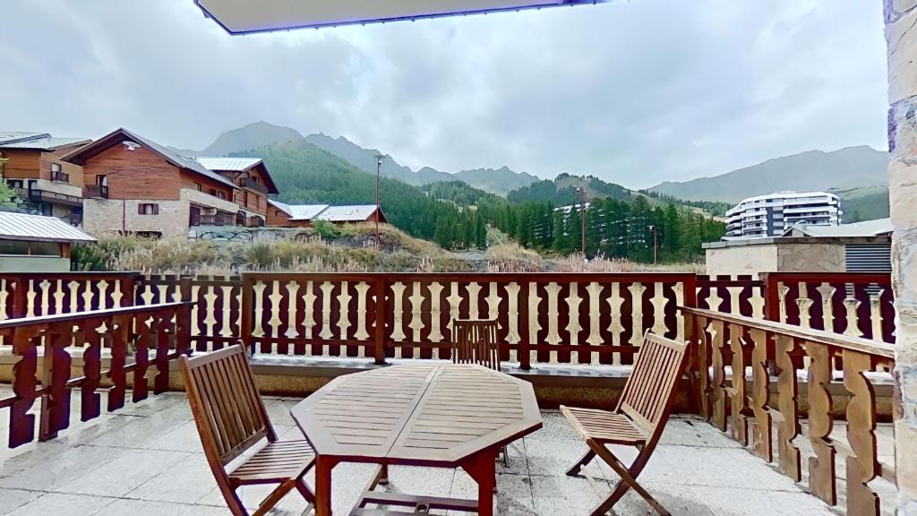 d'une table et de chaises sur un balcon avec une clôture. dans l'établissement CASA-Amélie terrasse vue parking, à Vars