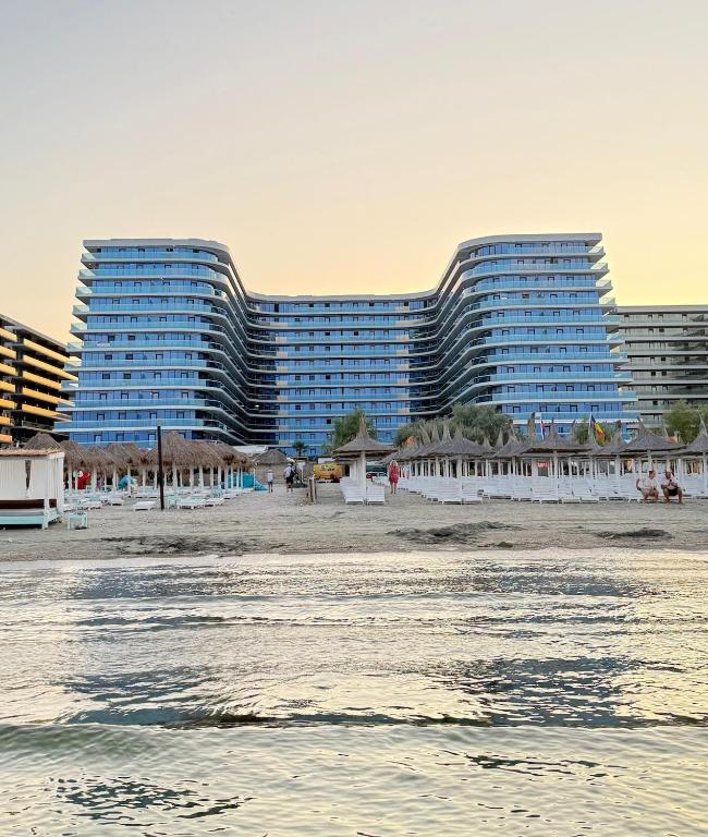 two tall buildings on the beach with the ocean at Alexander Studio White Titanic in Mamaia Sat/Năvodari