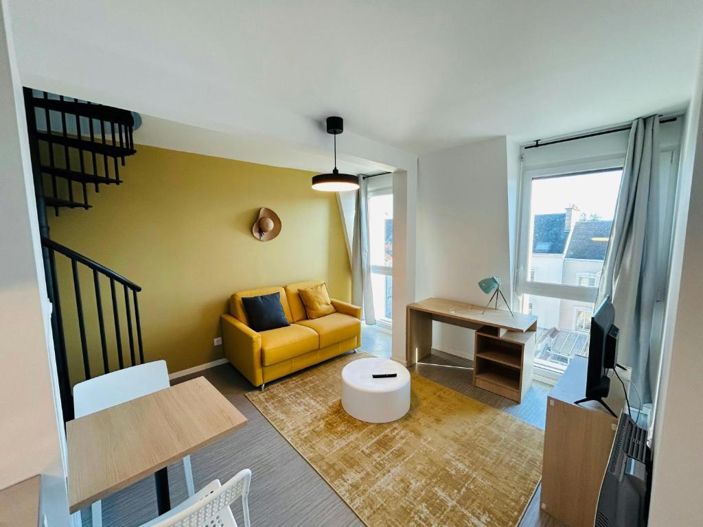 un salon avec un canapé jaune et une table dans l'établissement We Live In R - Duplex 503, à Reims