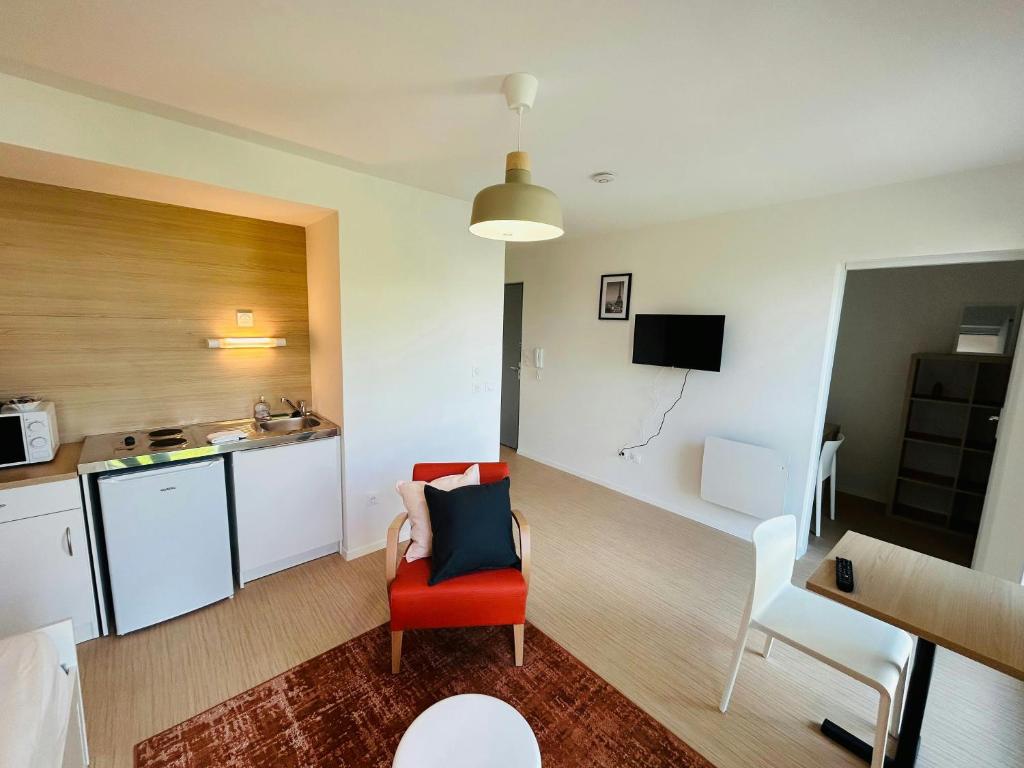 Il comprend un salon avec une chaise rouge et une cuisine. dans l'établissement We Live In R - Suite 304, à Reims