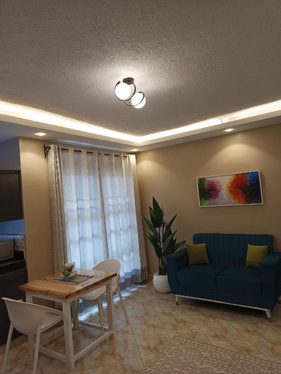 a living room with a blue couch and a table at Lerato's Apartments in Kampala