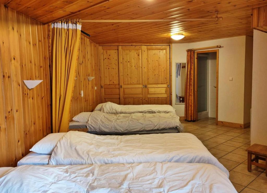 three beds in a room with wood paneling at Casa-Chalet du Merle N° 1 in Champagny-en-Vanoise