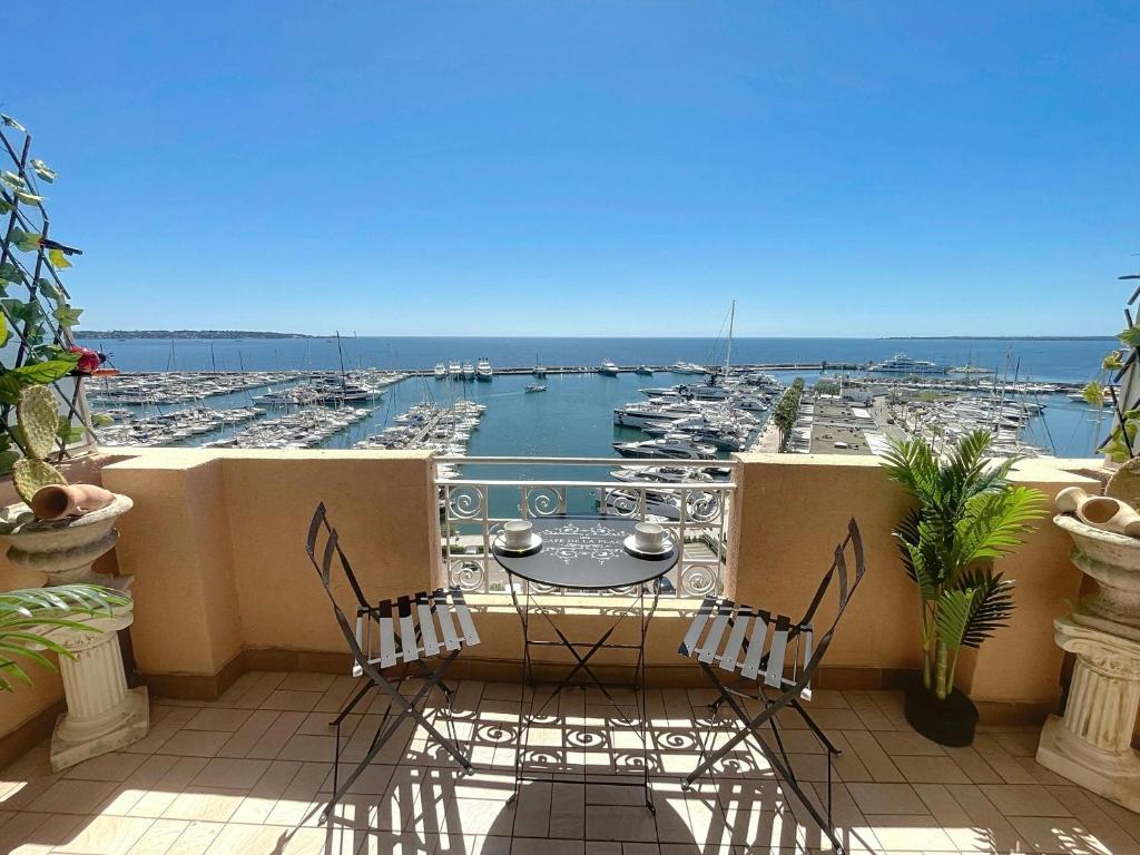 un balcon avec une table et des chaises et une vue sur un port dans l'établissement Grand Palais - 4 couchages - 1mezzanine - Vue mer, au Golfe-Juan