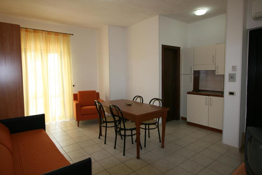 a living room with a table and chairs and a kitchen at Residence Club Barbara in Ostuni
