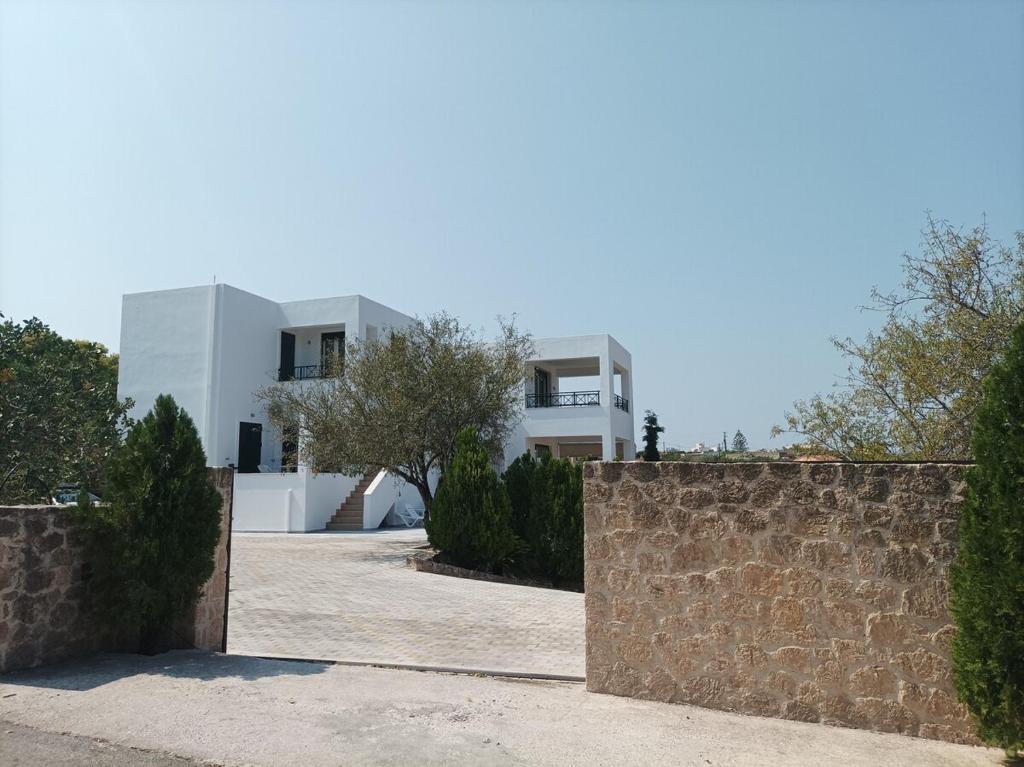 a house with a stone wall and a fence at Jimmy's Romantic Getaway in Egina