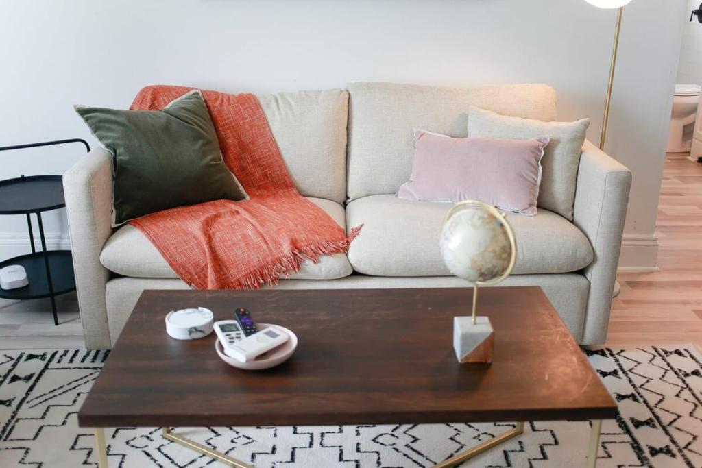 a living room with a couch with pillows and a table at Sojourn on the Bay 2 BR Private Beach Access in Norfolk