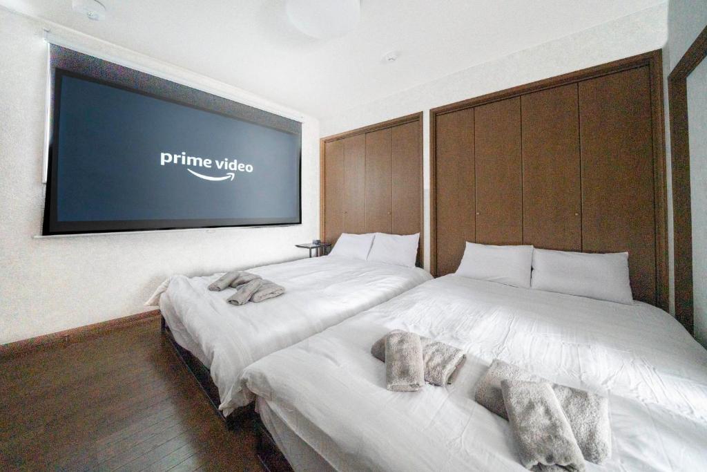 小樽市にあるKOTONOHA - Vacation STAY 19374のベッド2台、壁掛けテレビが備わる客室です。