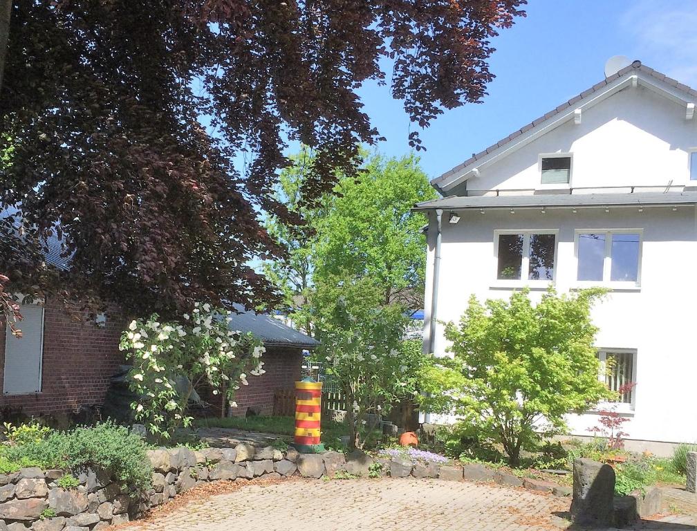 a white house with a stone fence in front of it at Ferienwohnung Jürgens in Rheinbreitbach