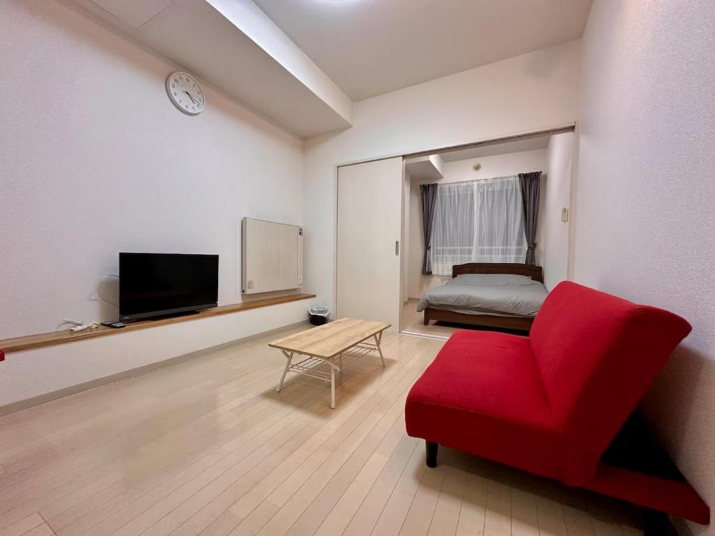 a living room with a red chair and a bed at Park Hills OM Chuo 12 - Vacation STAY 19390 in Sapporo