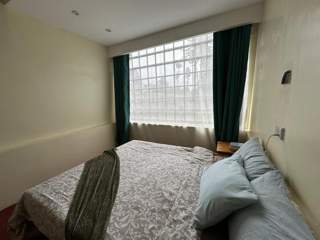 a bedroom with a bed in front of a window at The T Cottage in Othaya