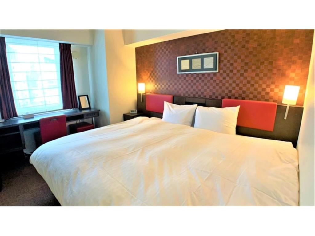 a hotel room with a large white bed and a desk at Smile Hotel Nagoya Sakae - Vacation STAY 66740v in Nagoya
