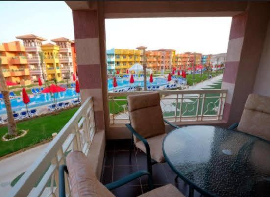 a balcony with a table and chairs and a view of a pool at porto south beach from amer group شاليه فندقى من عامر جروب فى بورتو ساوث بيتش منطقه التايم شير المميزه in Ain Sokhna