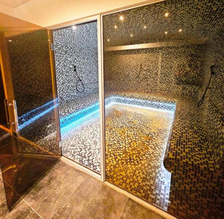 bagno con doccia e parete a mosaico di Apartman B64 Residence Hill Kopaonik a Kopaonik